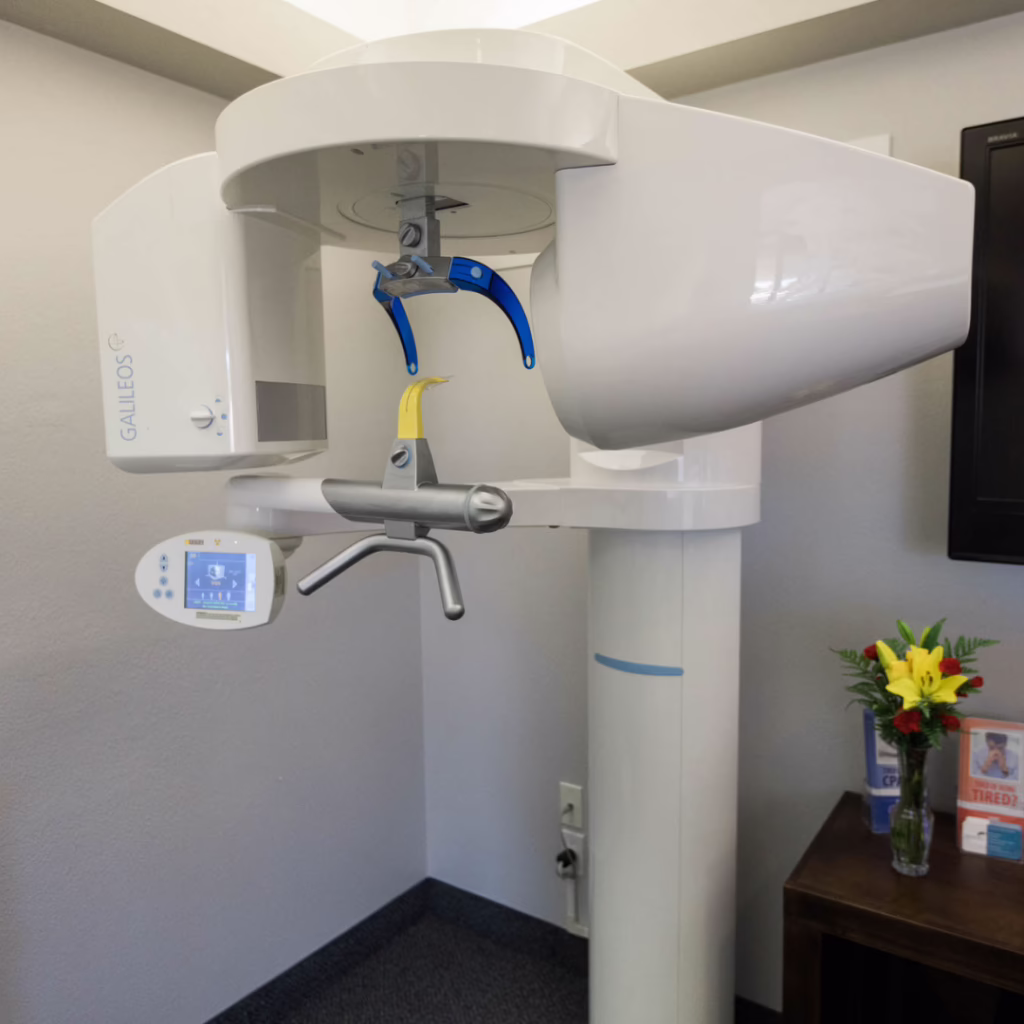 Dental panoramic X-ray or CBCT machine in a dental clinic, with patient positioning arm and control panel visible.